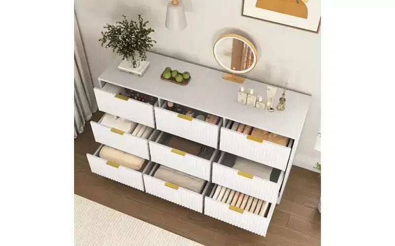 Grand chiffonnier en bois de 160 cm à neuf tiroirs, adapté aux chambres à coucher. Les façades des tiroirs présentent un motif ondulé. Blanc