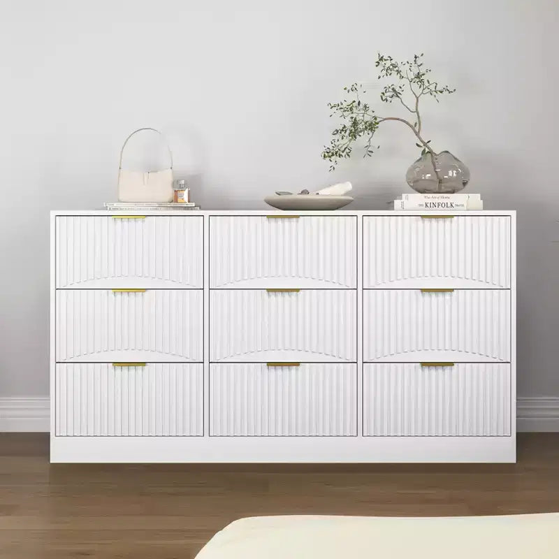 Grand chiffonnier en bois de 160 cm à neuf tiroirs, adapté aux chambres à coucher. Les façades des tiroirs présentent un motif ondulé. Blanc